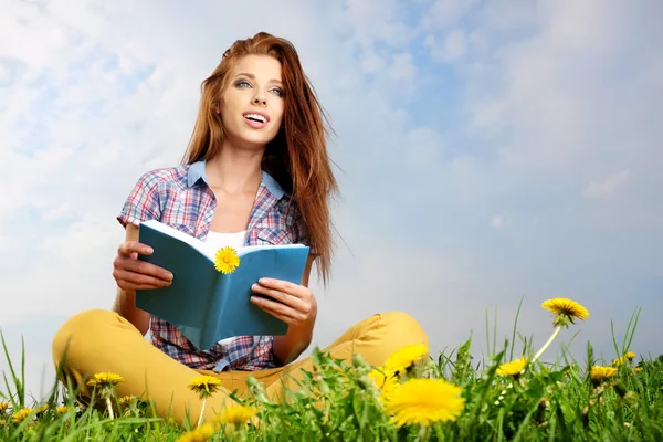 Mooi meisje met boek op gras — Stockfoto