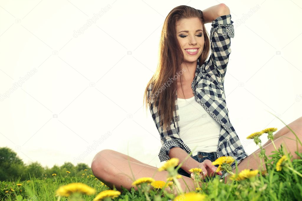 Portrait of young beautiful brunette woman sitting on grass