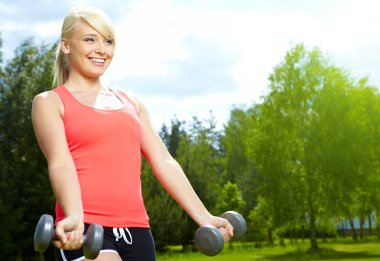 yeşil park dumbbell ile egzersiz yaparak güzel bir genç kadın