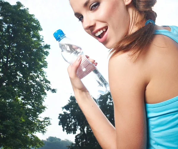 Молодая женщина пьет воду на открытом воздухе тренировки — стоковое фото