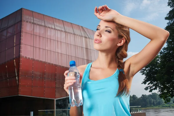 Молодая женщина пьет воду на открытом воздухе тренировки — стоковое фото