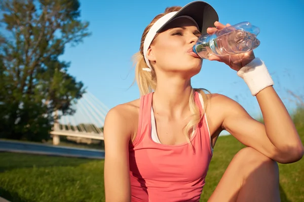 Jonge vrouw drinkwater bij buitenshuis training — Stockfoto