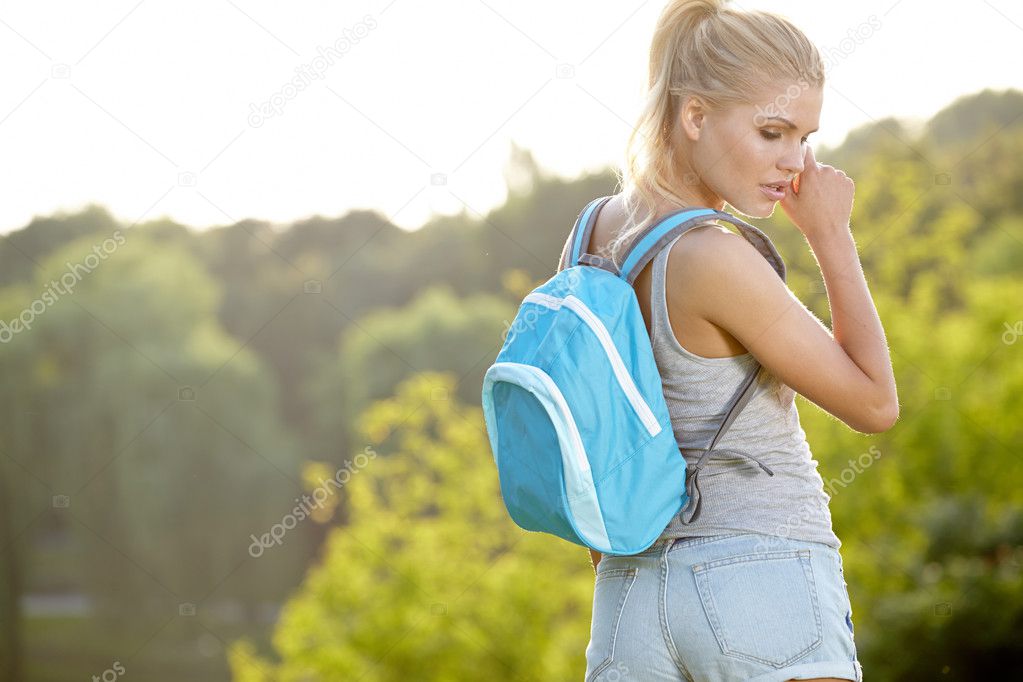 young blond woman hiking with scenery in thegreen landscape back