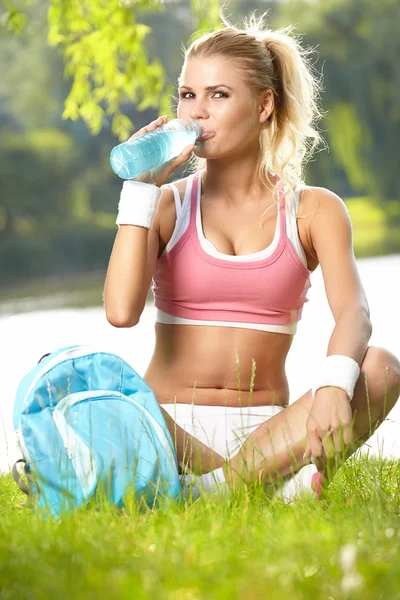 Sedienta mujer deportiva beber agua después del entrenamiento — Foto de Stock