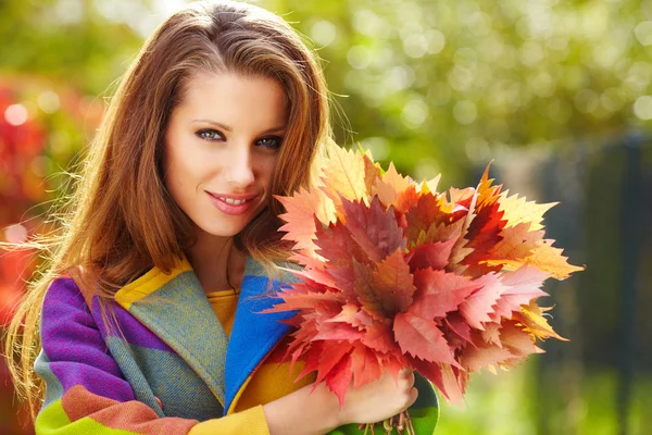 Beautiful elegant woman standing in a park in autumn — Stock Photo, Image