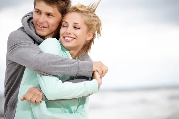 Couple running on beach holding hands smiling — Stock Photo, Image