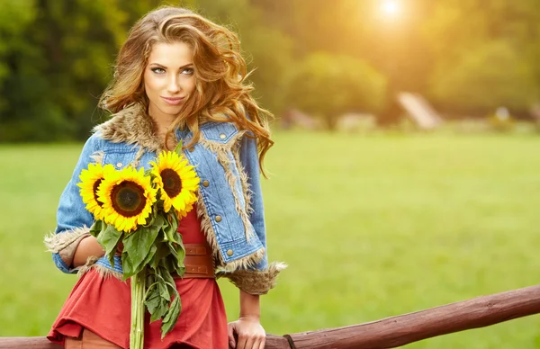 Jeune femme de mode avec un bouquet de tournesols dans le domaine — Photo