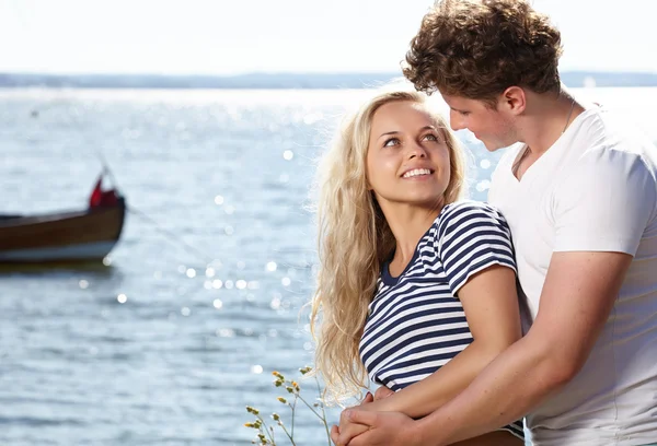 Jonge mooie paar verliefd zitten in de buurt van het water — Stockfoto