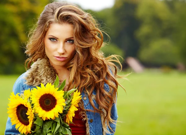 Giovane donna di moda con un mazzo di girasoli nel campo — Foto Stock