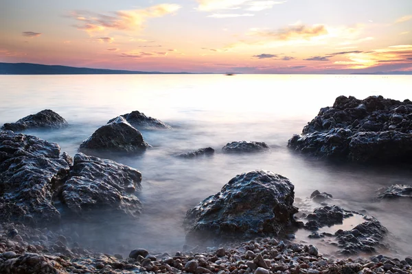 Sunrise kayalık deniz kıyısı ve bulanık su — Stok fotoğraf