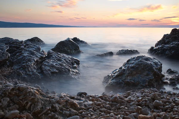 Salida del sol en la costa rocosa del mar y agua borrosa — Foto de Stock