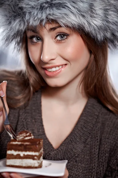 Beautiful winter woman eating cake — Stock Photo, Image