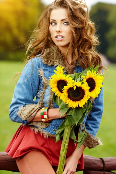 Jovem mulher da moda com um buquê de girassóis no campo — Fotografia de Stock