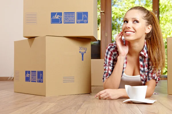 A beautiful single young woman unpacking boxes and moving into a — Stock Photo, Image