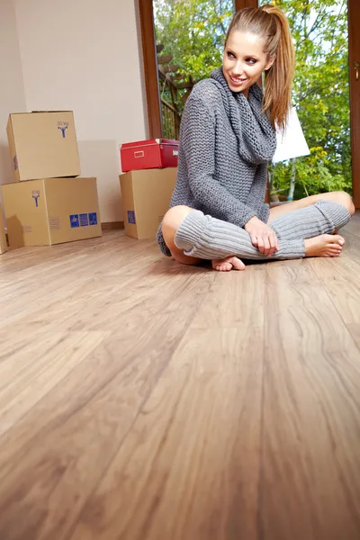 A beautiful single young woman unpacking boxes and moving into a — Stock Photo, Image