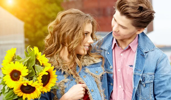 Люблячий молодий чоловік обіймає свою дівчину соняшниками в їх — стокове фото