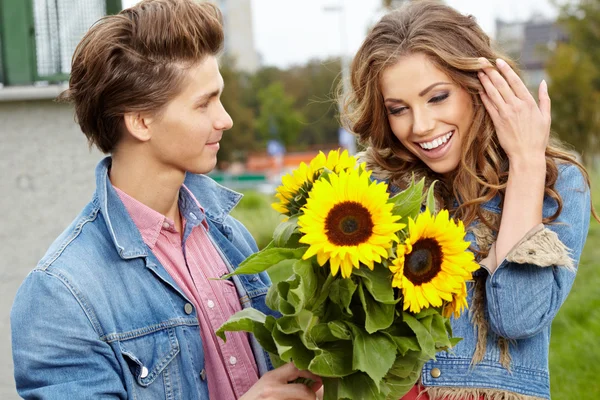 Loving young man hugging his girlfriend with sunflowers in their — Stock Photo, Image