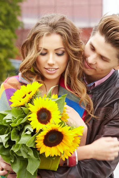 Kochający mężczyzna młody przytulanie dziewczyną z słoneczniki w ich — Zdjęcie stockowe