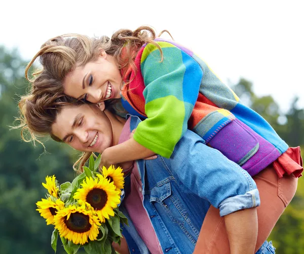 Loving young man hugging his girlfriend with sunflowers in their — Stock Photo, Image