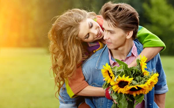 Amour jeune homme étreignant sa petite amie avec des tournesols dans leur — Photo