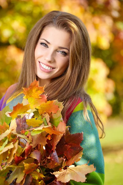 Молодая женщина с осенними листьями в руке — стоковое фото