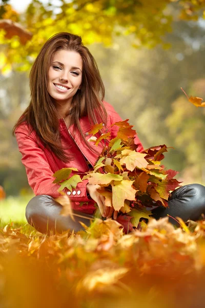 Jonge vrouw met herfst bladeren in de hand — Stockfoto