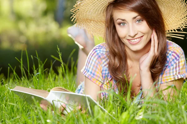 Kız öğrenci bir kitap ile çim üzerinde yalan — Stok fotoğraf