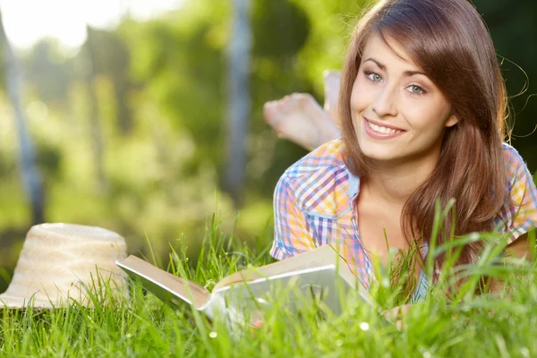 Étudiante couchée sur l'herbe avec un livre — Photo