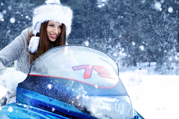 Smiling young woman riding a snowmobile — Stock Photo, Image