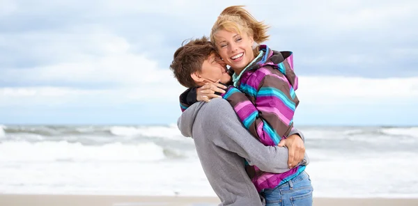 Casal abraçando na costa atrás do céu azul — Fotografia de Stock