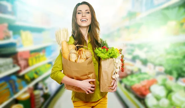 Mujer joven sosteniendo una bolsa llena de pan — Foto de Stock