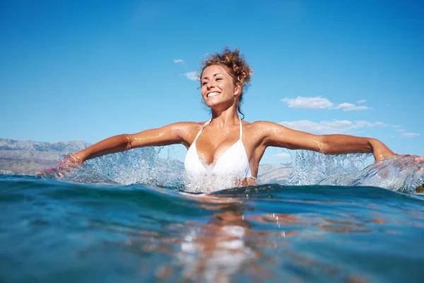 Woman in the sea splashing water — Stock Photo, Image