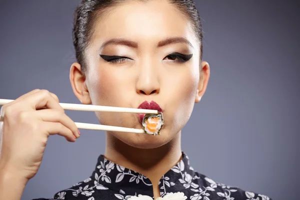 Sushi donna in possesso di sushi con bacchette guardando la fotocamera — Foto Stock