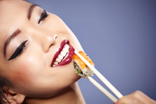 Sushi vrouw met sushi met stokjes te kijken naar de camera — Stockfoto