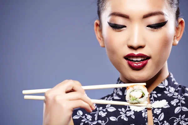 Sushi vrouw met sushi met stokjes te kijken naar de camera — Stockfoto