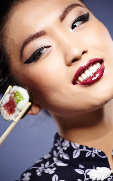 Sushi vrouw met sushi met stokjes te kijken naar de camera — Stockfoto