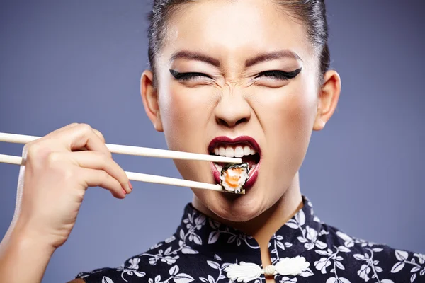 Sushi femme tenant des sushis avec des baguettes regardant la caméra — Photo