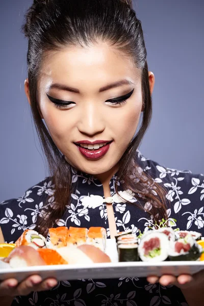 Sushi mujer sosteniendo sushi con palillos mirando a la cámara — Foto de Stock