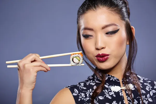 Mulher segurando sushi com pauzinhos — Fotografia de Stock