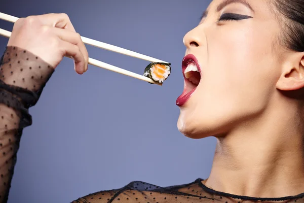 Woman holding sushi with chopsticks — Stock Photo, Image