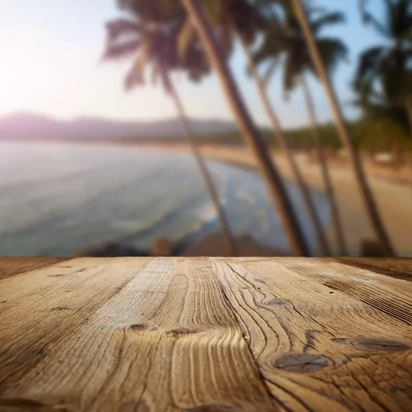 Mesa de madeira na praia com palmas — Fotografia de Stock