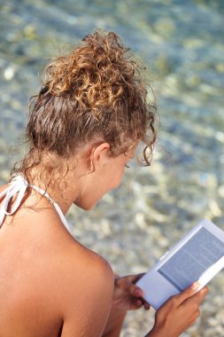 kadın tatilde plajda bir kitap okuma