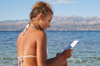 kadın tatilde plajda bir kitap okuma