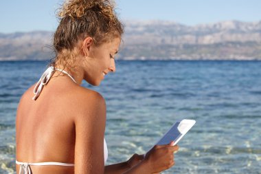 kadın tatilde plajda bir kitap okuma