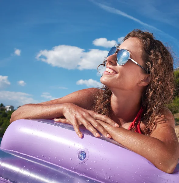 Woman having fun on pink air bed in sea — Stock Photo, Image