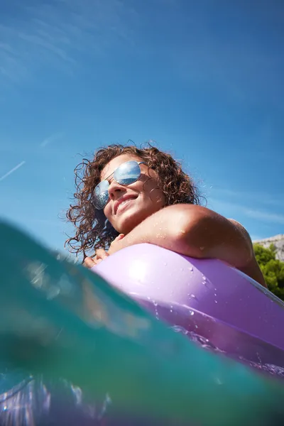 Woman having fun on pink air bed in sea — Stock Photo, Image