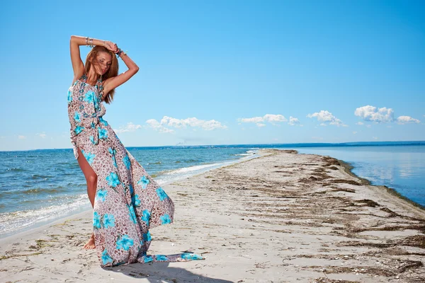 Vrouw in een blauwe jurk op de oceaan kust — Stockfoto