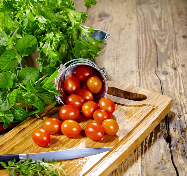 Tomates cherry con albahaca sobre una mesa de madera —  Fotos de Stock