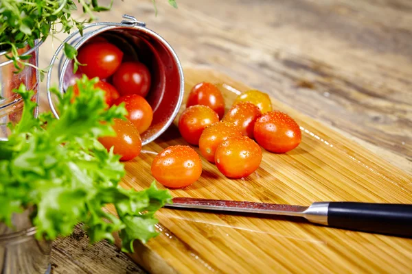 Черри помидоры с базиликом на деревянном столе — стоковое фото