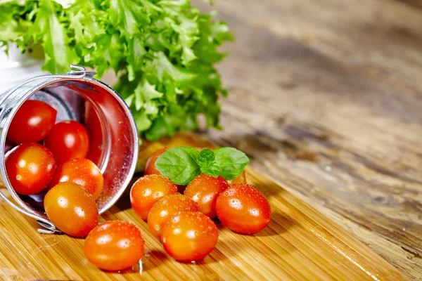 Tomates cherry con albahaca sobre una mesa de madera —  Fotos de Stock